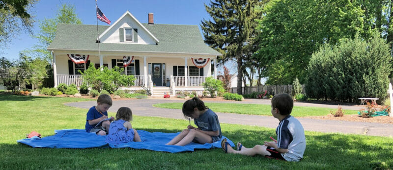 kid coloring outside the farmhouse